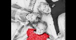 3 Kindergartenkinder liegen am Rücken auf d. Boden, Köpfe zueinander, sich an d. Händen haltend, lachen in Kamera. In Graustufen, 1 Shirt rot. © contrastwerkstatt|stock.adobe.com|bearb.Caritas FRG